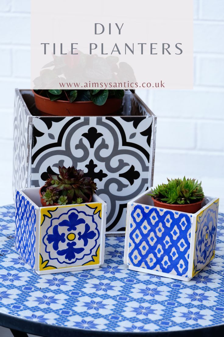 three planters sitting on top of a table with blue and white tiles around them