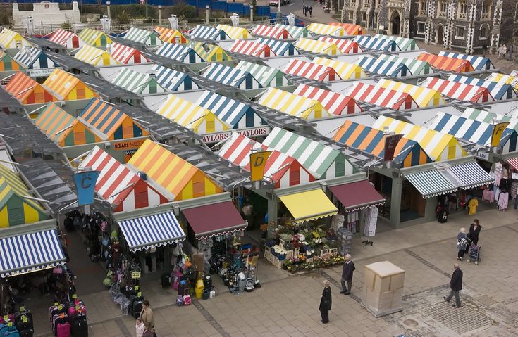 an aerial view of many tents with people walking around them and buildings in the background