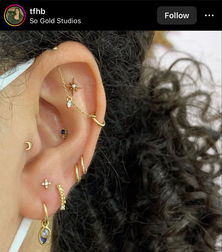 a woman wearing ear piercings with stars and moon designs on her ears, in front of the camera