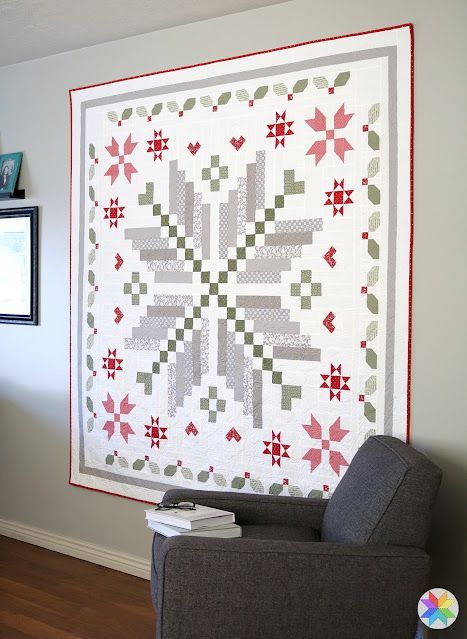 a living room with a gray chair and a quilt on the wall