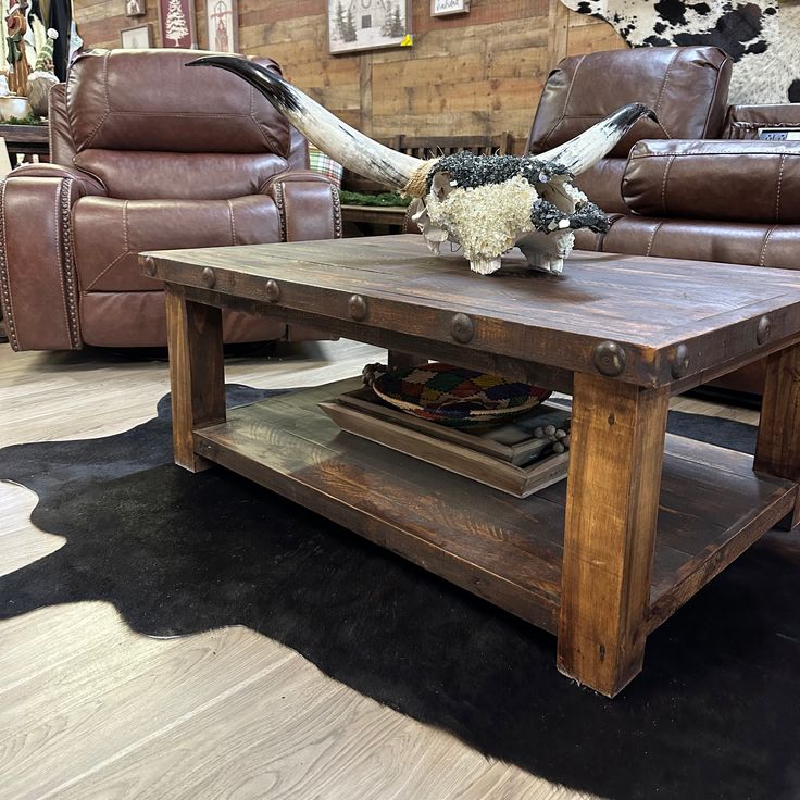 a living room with two couches and a coffee table in front of a cow skull