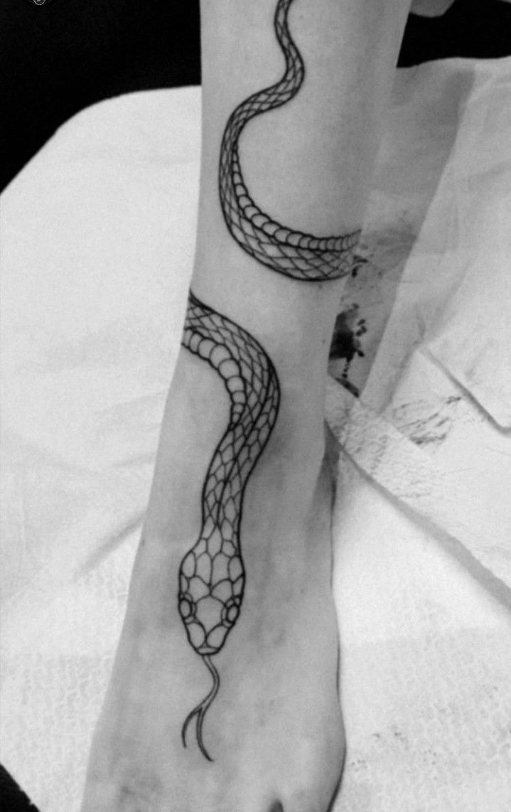 a black and white photo of a person's foot with a snake tattoo on it