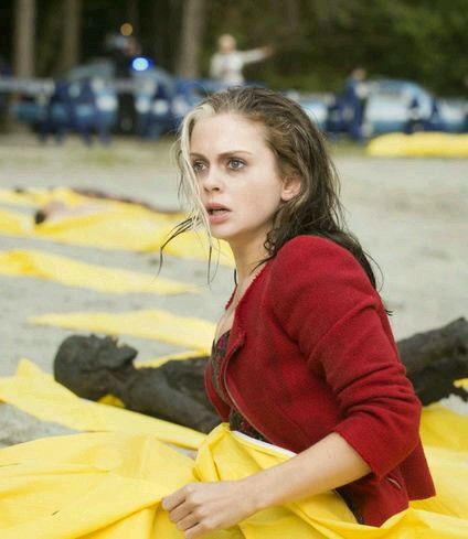 a woman sitting on the ground in front of yellow caution tape with her eyes closed