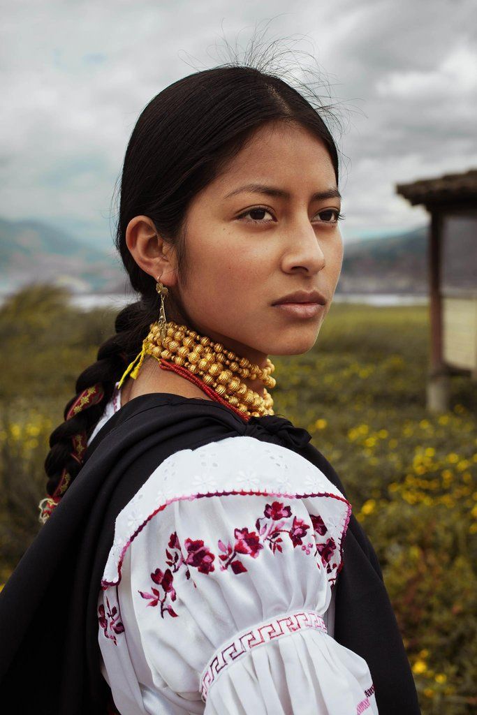 a woman with braids and jewelry standing in front of a field full of flowers