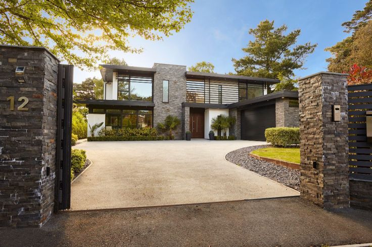 the entrance to a large modern home with stone pillars and brick columns on either side