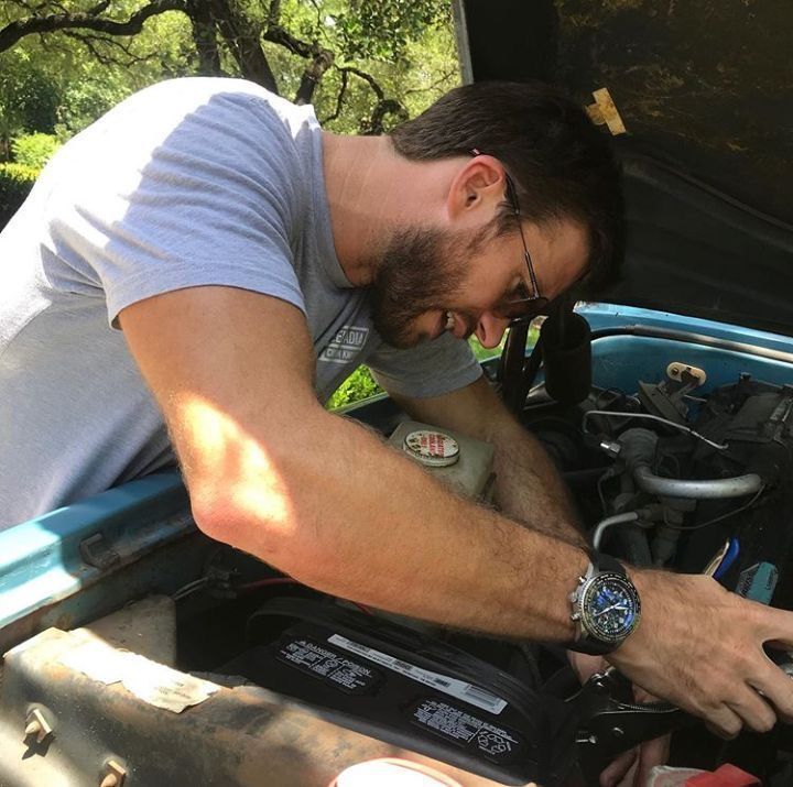 a man is working on an engine in the back of a truck with his hand on the hood