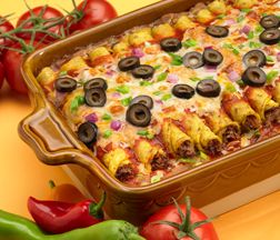 a casserole dish with olives, onions and peppers on the side next to tomatoes