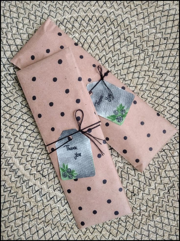 two pieces of pink paper with black polka dots on them are tied up and sitting next to each other