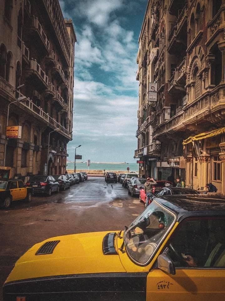 a yellow taxi cab is parked on the side of an empty street in front of tall buildings