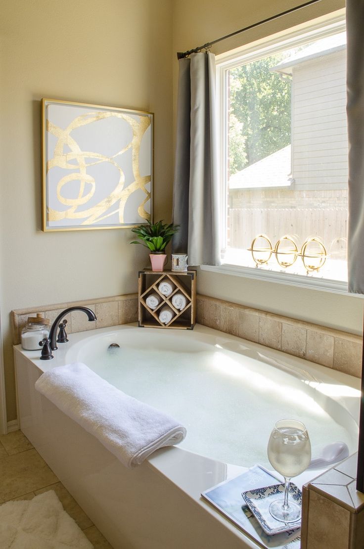 a bathroom with a large bathtub next to a window and a painting on the wall