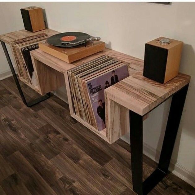 a record player is sitting on top of a wooden table with vinyl records in front of it