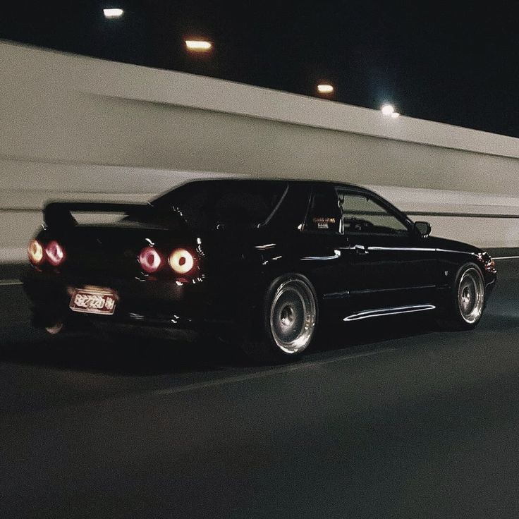 a black car driving down the road at night