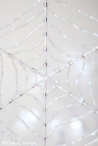 a spider web hanging from the ceiling in front of a wall with lights on it