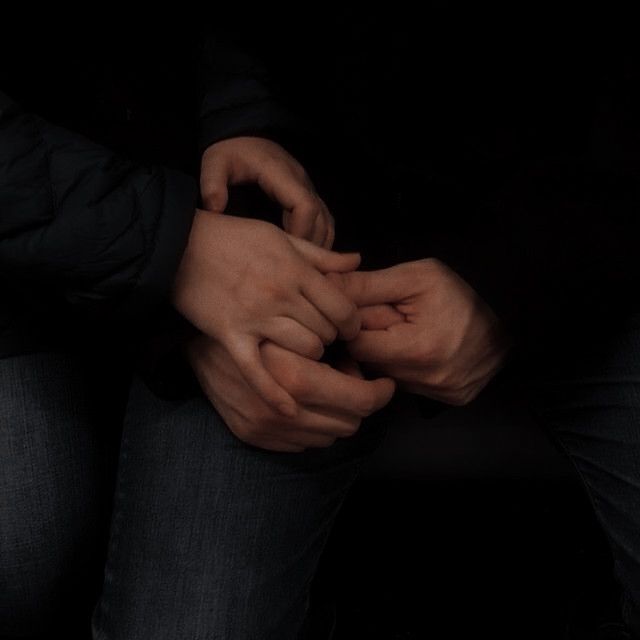 two people holding hands in the dark with their hands on each other's chest