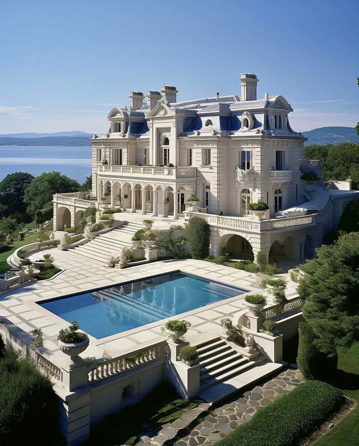 an aerial view of a large mansion with a pool in the foreground and stairs leading up to it