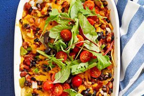 a casserole dish with tomatoes, black olives and spinach