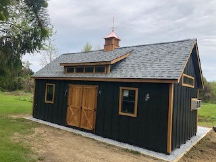 a small black barn with a brown roof