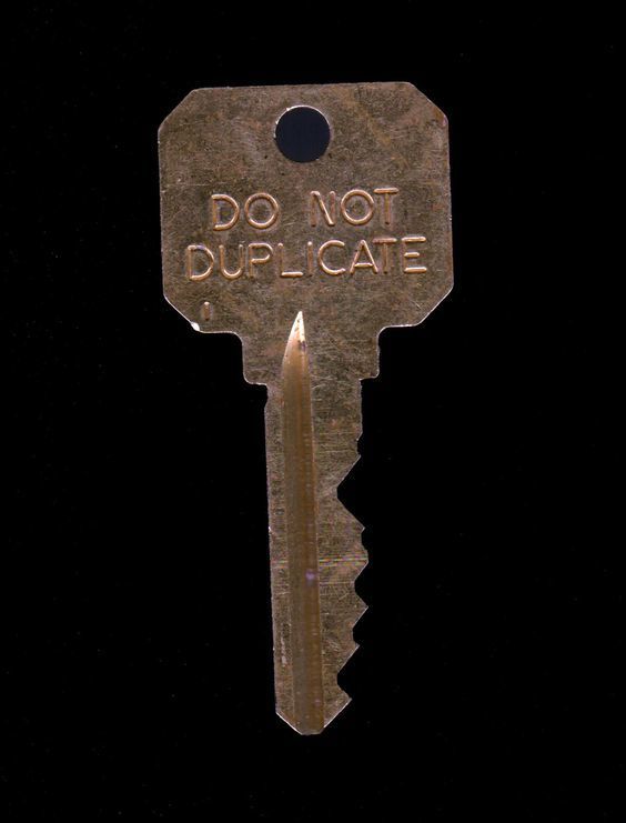 an old key with the words do not duplate written on it is shown against a black background