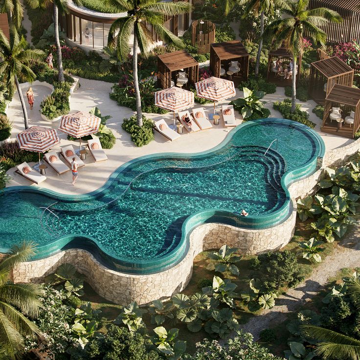 an aerial view of a resort pool with lounge chairs and umbrellas in the foreground