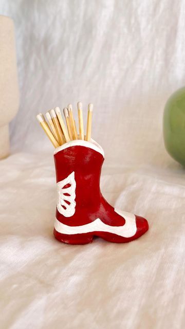 a red boot with toothpicks in it sitting on a bed next to an apple