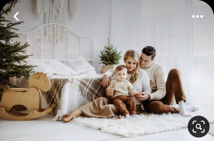 a man and woman are sitting on the floor with a baby in front of them