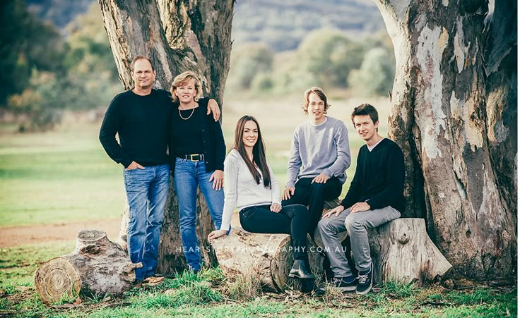 a group of people standing next to each other in front of two large tree stumps