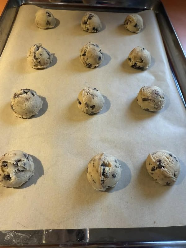 doughnuts are lined up on a baking sheet ready to go into the oven