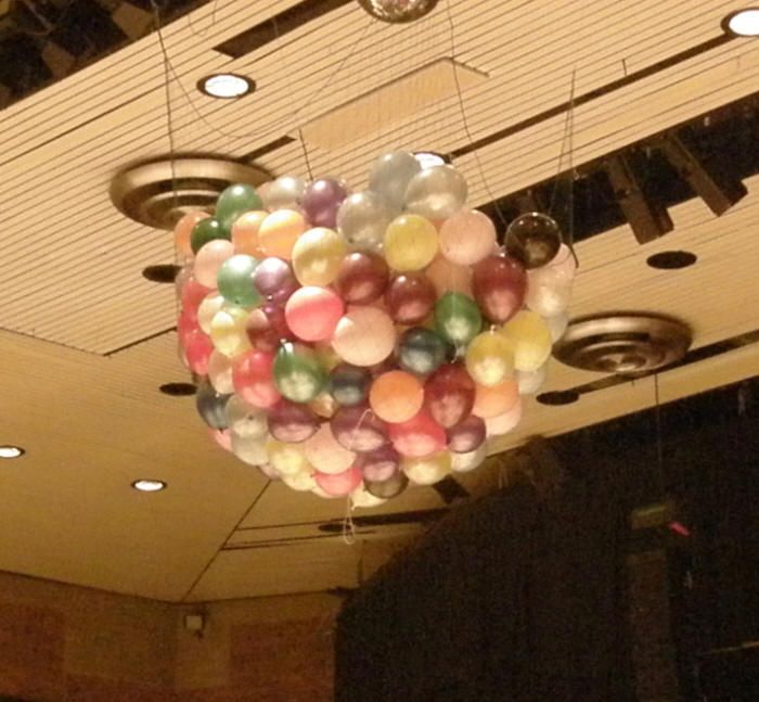 a bunch of balloons hanging from the ceiling in a room with lights and chandelier