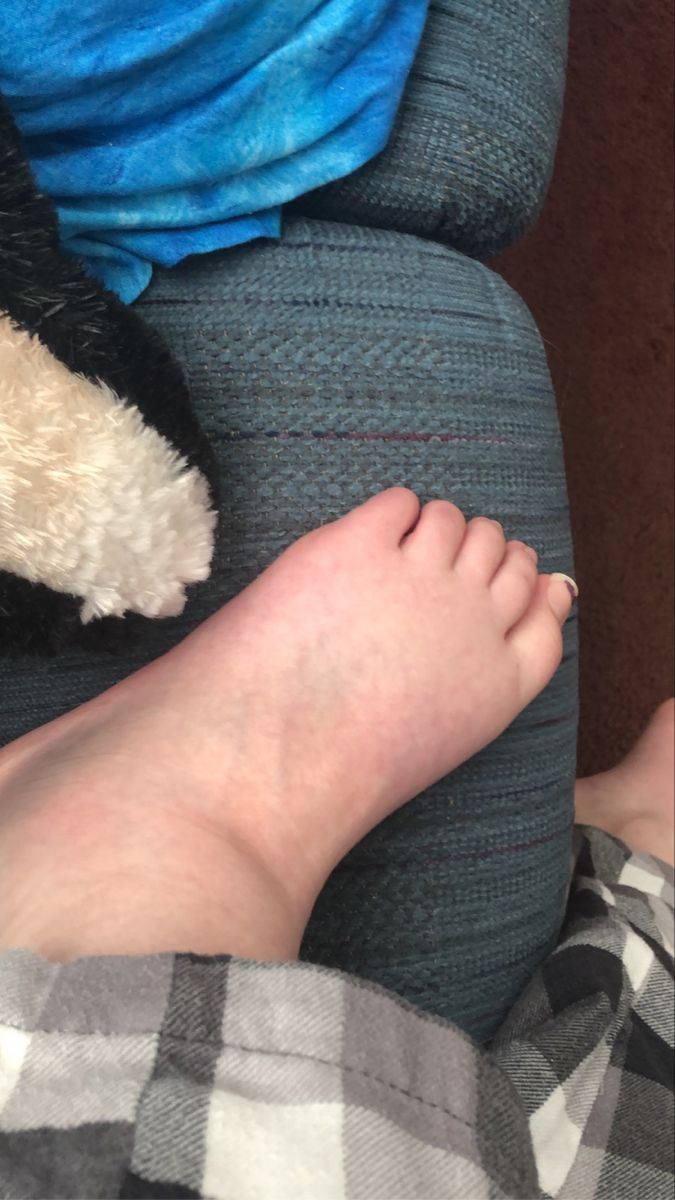 a person's foot resting on the back of a couch next to a stuffed animal