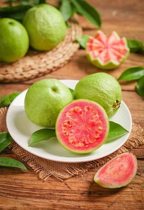 a white plate topped with green and red fruit next to sliced watermelon on top of a wooden table