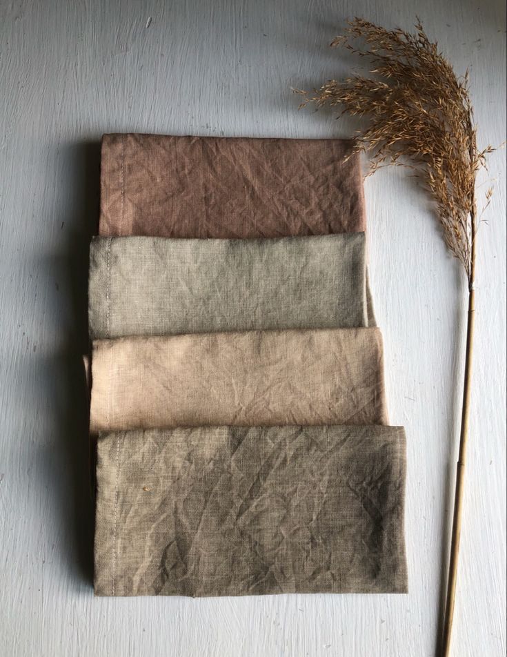 four different shades of fabric next to a dried plant