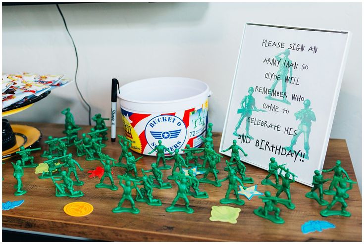 green plastic army men are on the table next to a sign