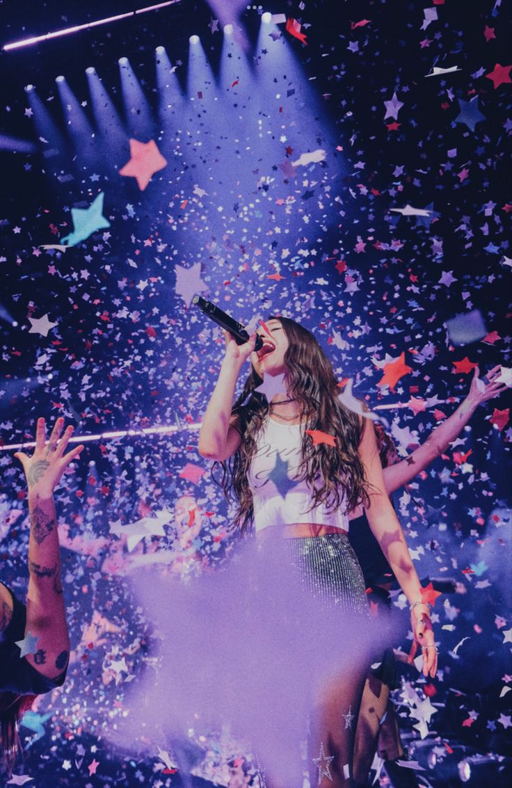 a woman standing on top of a stage with confetti in the air behind her