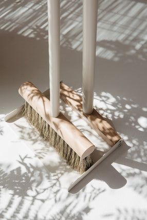 two brushes are placed next to each other on a white surface with shadows from the floor