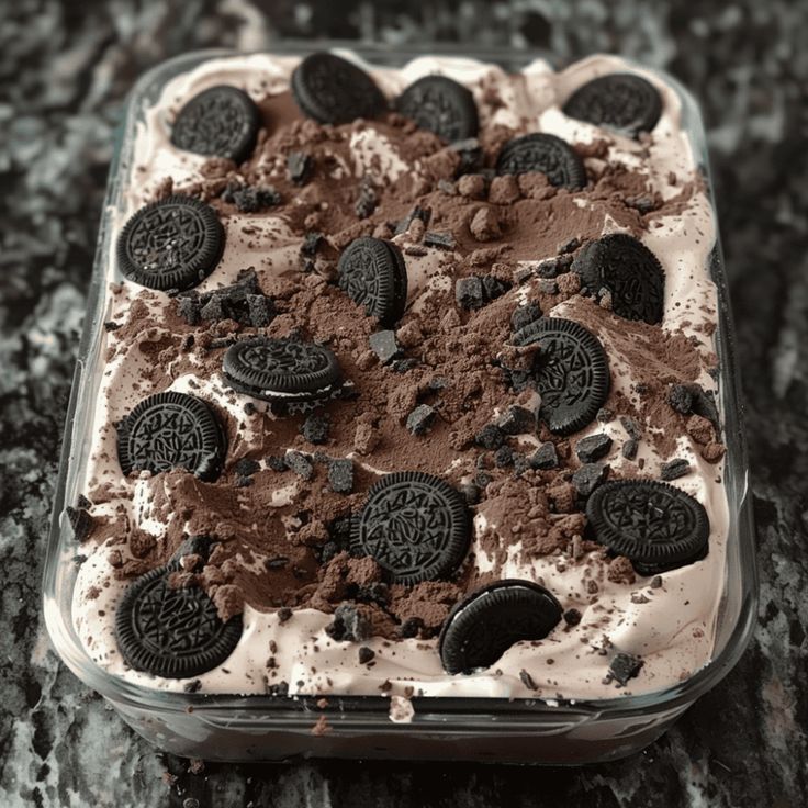 an ice cream sundae with oreo cookies and chocolate chips in it on a granite countertop