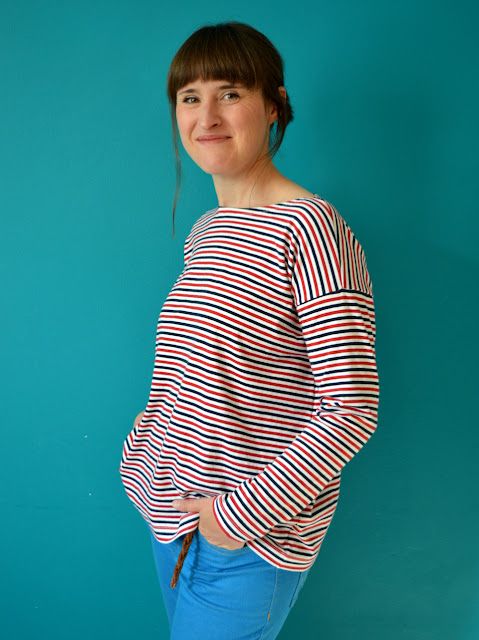 a woman standing in front of a blue wall with her hands on her hips and looking at the camera