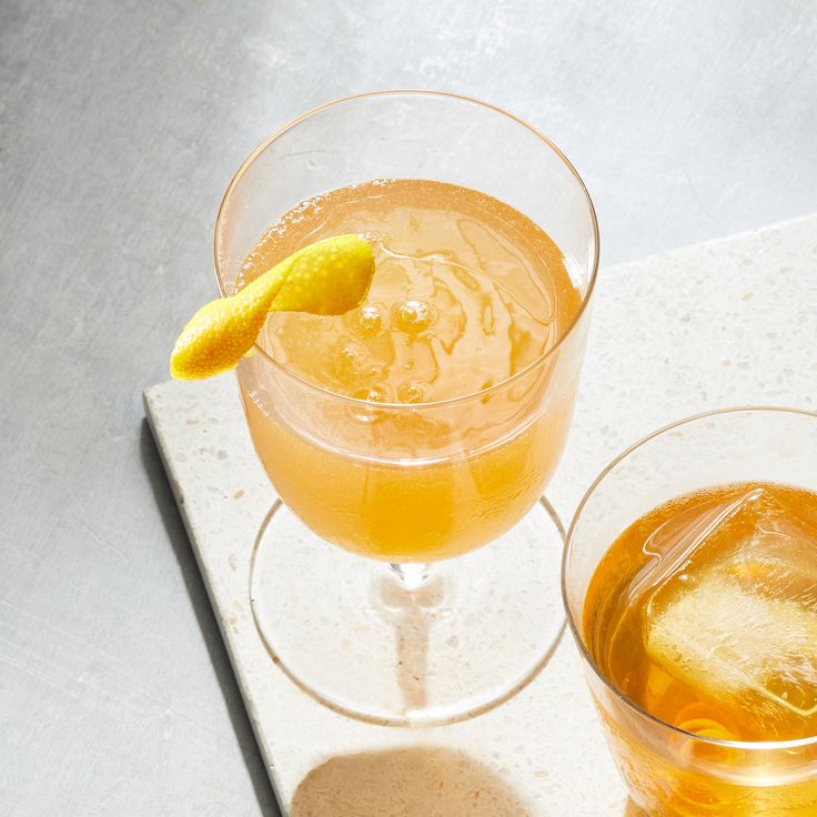 two glasses filled with drinks sitting on top of a white counter next to each other