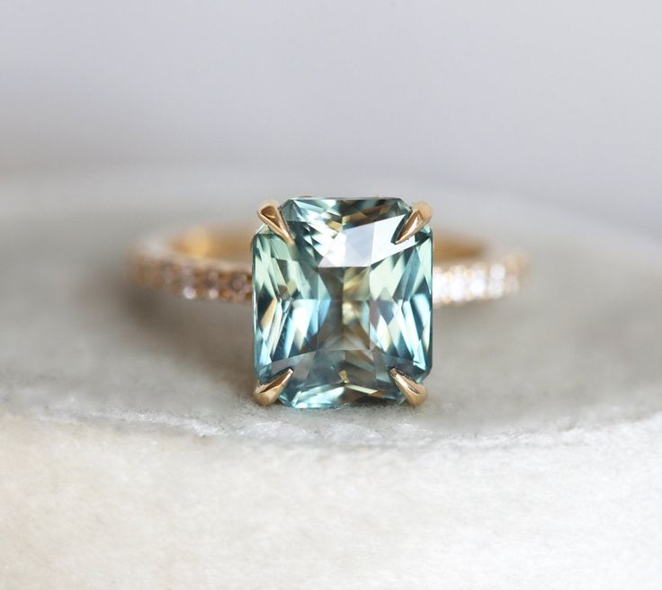 a ring with an aqua blue topazte surrounded by white and brown diamonds on a table