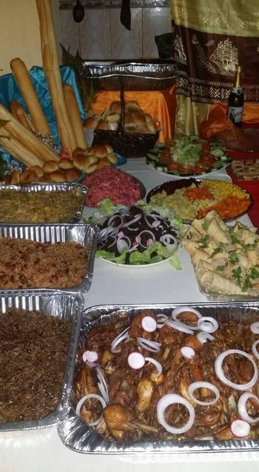 several trays filled with food sitting on top of a white tablecloth covered table