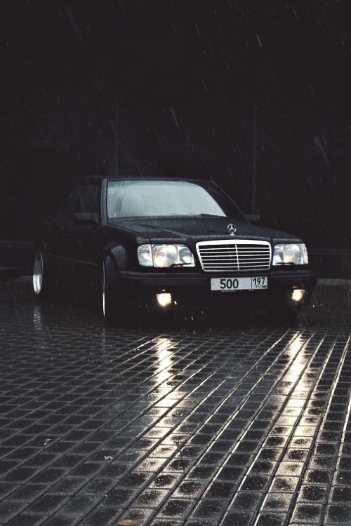 a black car parked in the rain at night