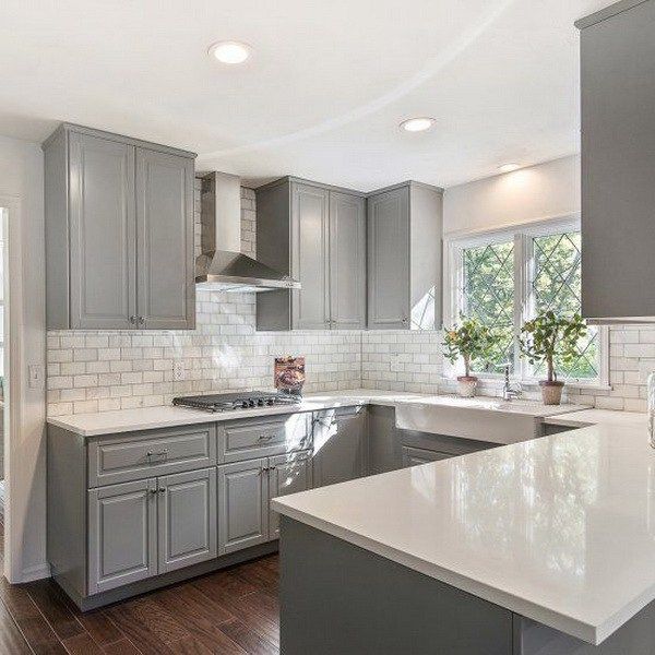 a large kitchen with gray cabinets and white counter tops, along with hardwood floorsing