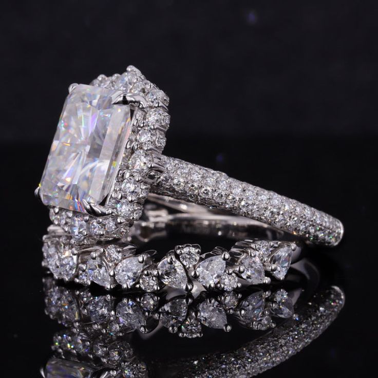 an engagement ring and wedding band set with a large diamond center surrounded by smaller diamonds