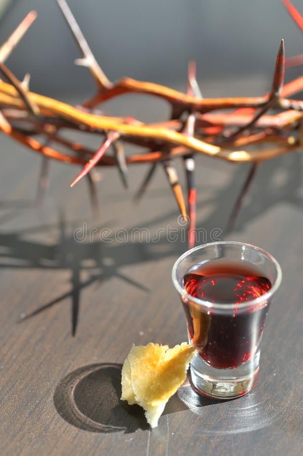 a shot glass filled with liquid sitting on top of a wooden table next to a crown of thorn