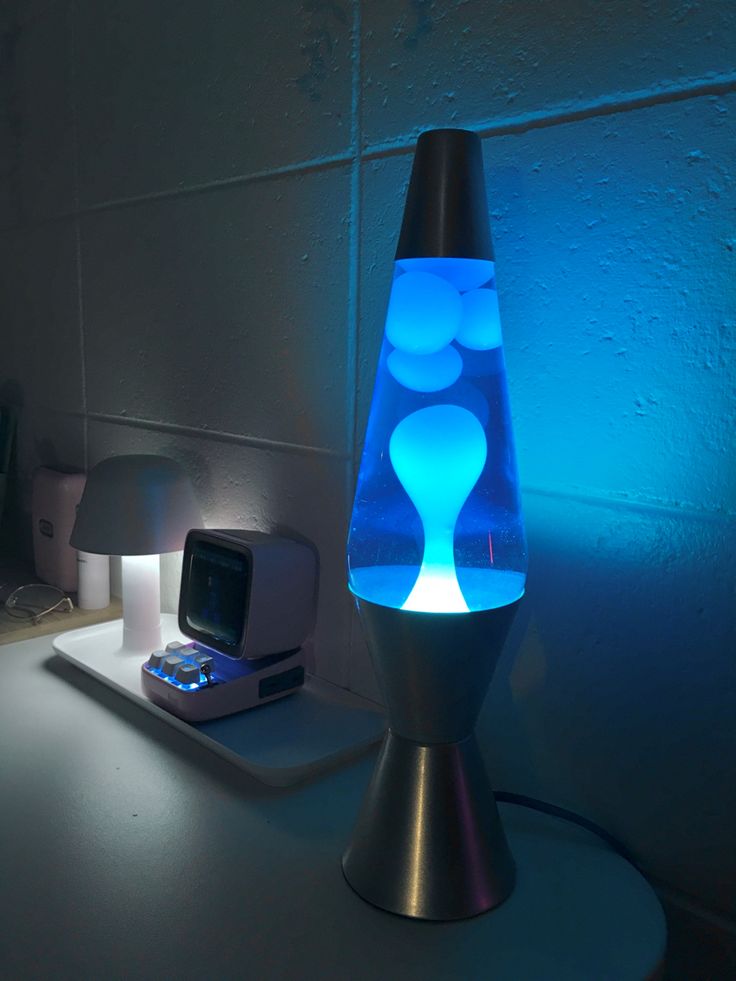 a lamp that is sitting on top of a table next to a cell phone and remote control