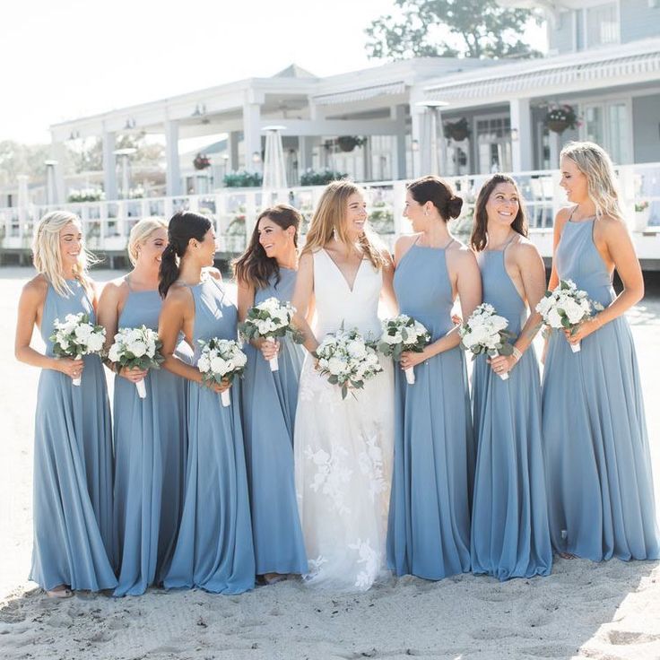 a group of women standing next to each other on top of a sandy beach covered in white flowers