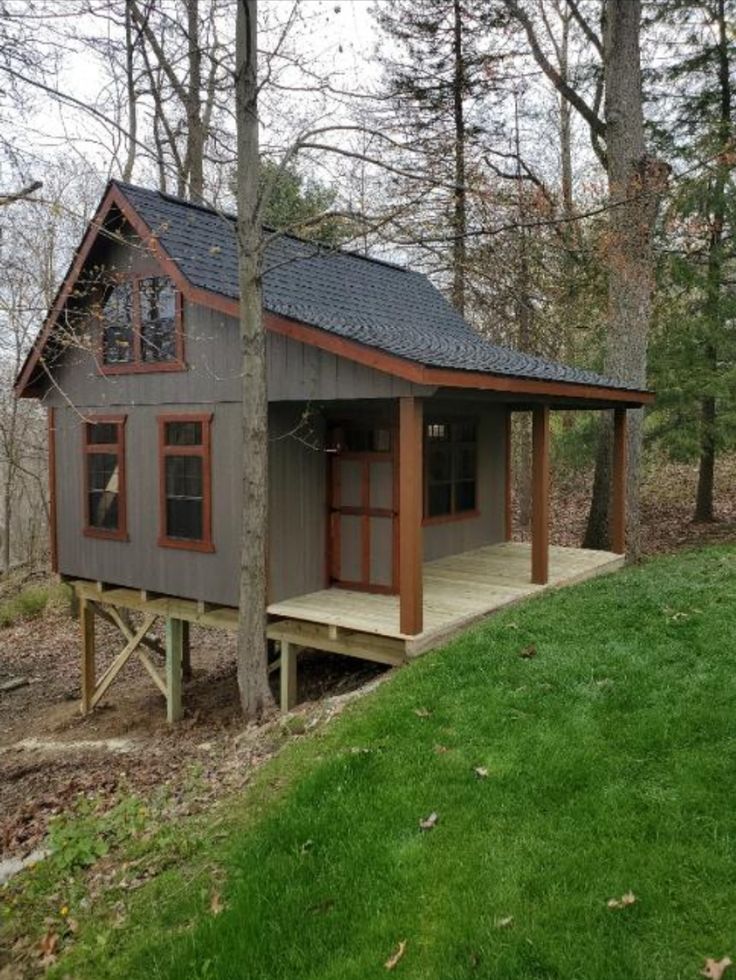 a small cabin in the woods with grass and trees