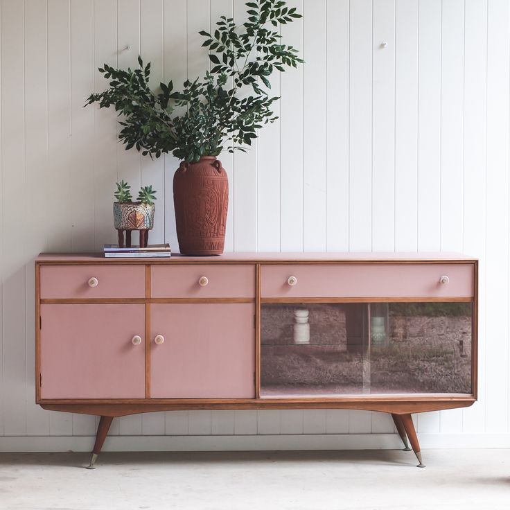 a pink sideboard with plants on top