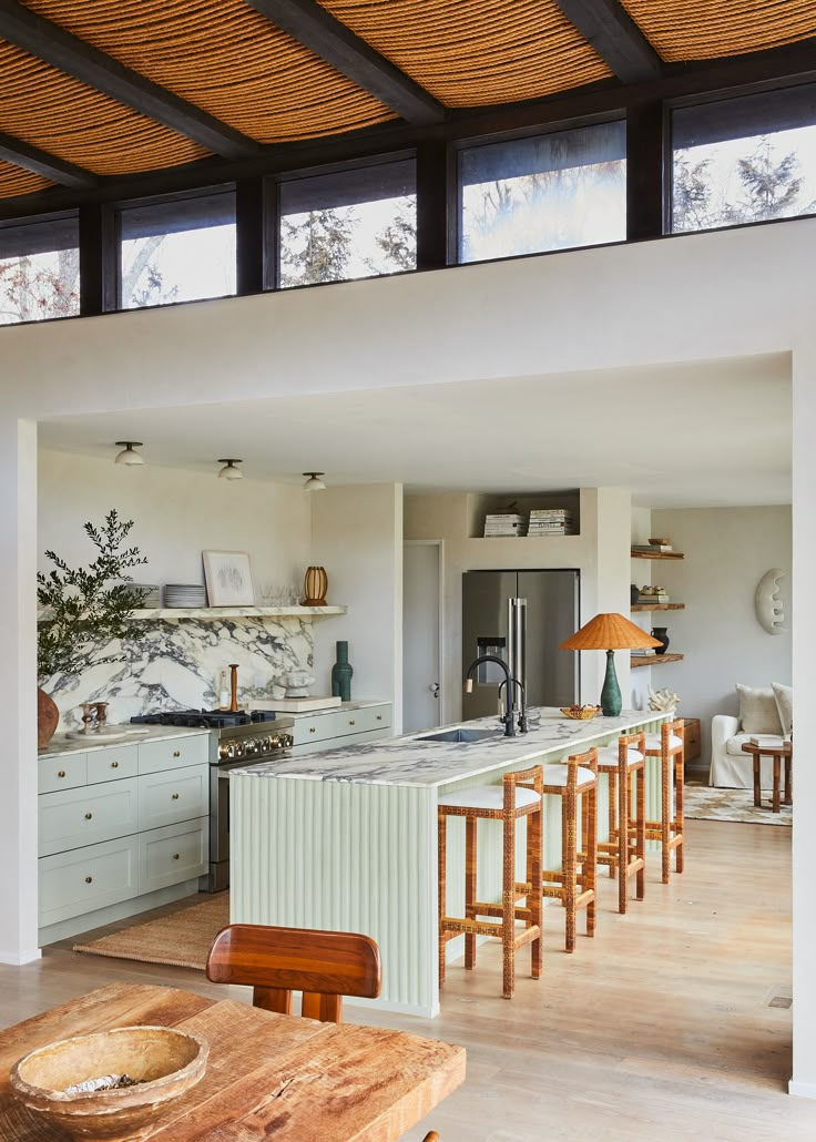 an open kitchen and dining area with wood flooring, white cabinets and counter tops