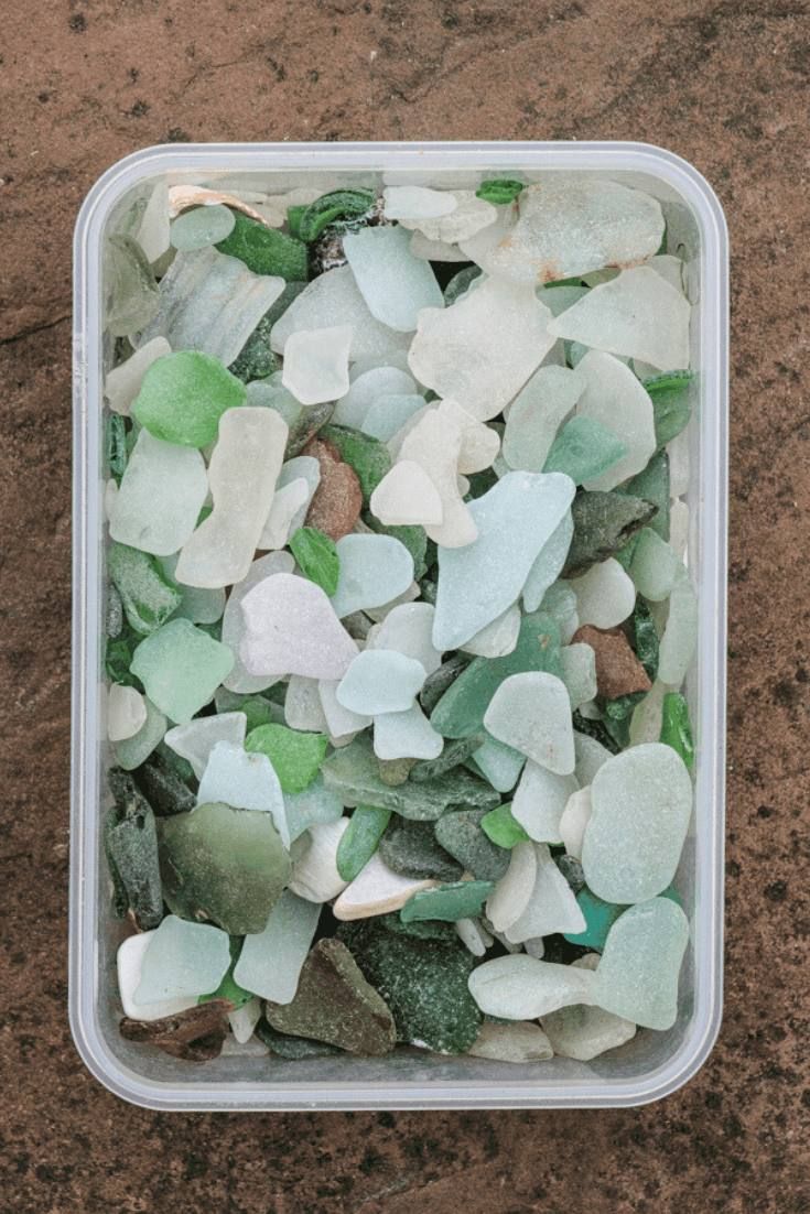 a plastic container filled with sea glass on top of a table