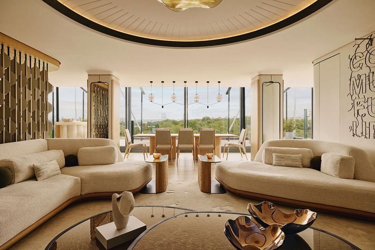 a living room filled with lots of furniture next to a large glass window covered wall